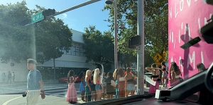 Design District, NE 39th Street in Miami: crowd taking selfies at the pink mural wall, seen from a car