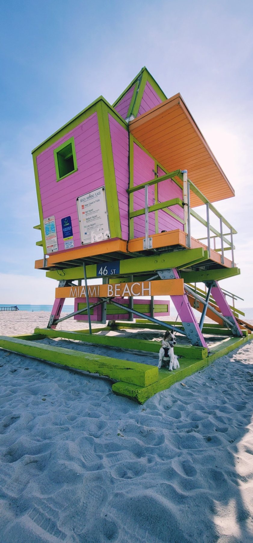 Pink, green and orange 46th Street lifeguard tower in Miami Beach with white sand and blue sky